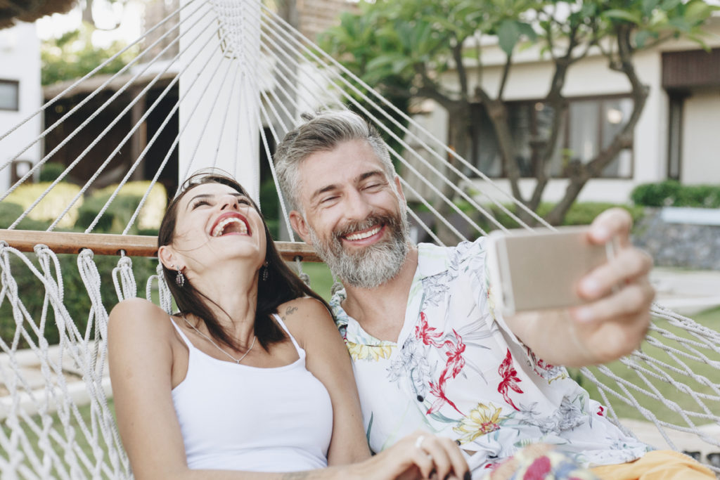 couple laughing and taking photos in a hammock