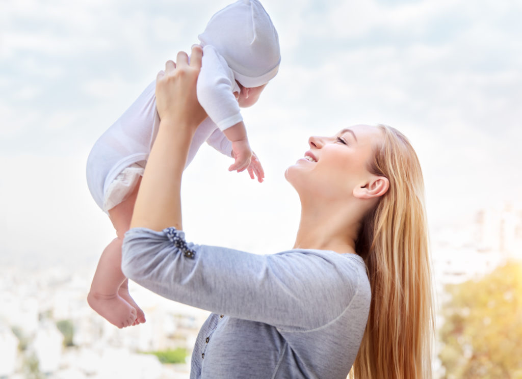 young blonde mother smiling and holding baby