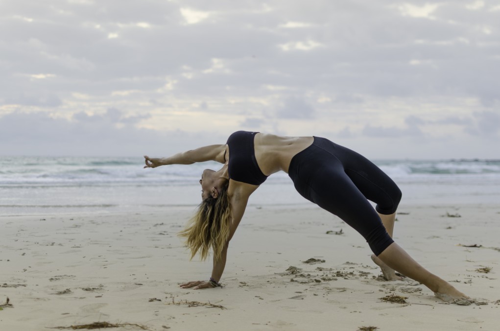 blonde woman doing yoga on the beach