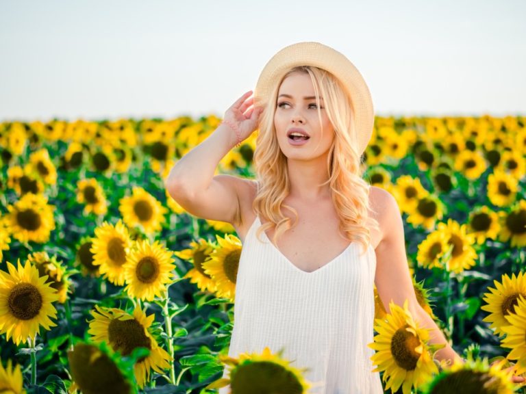 young blonde woman with a hat in sunflower field
