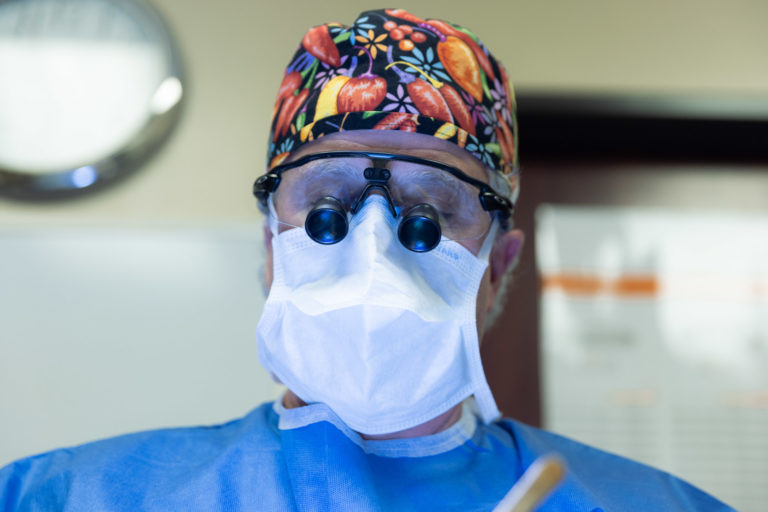 surgeon with protective eyewear and mask on by light