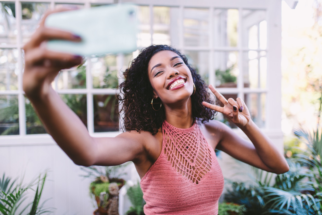 woman smiling and making a peace sign for a selfie