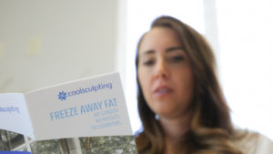 woman reading pamphlet for CoolSculpting Elite Near Me