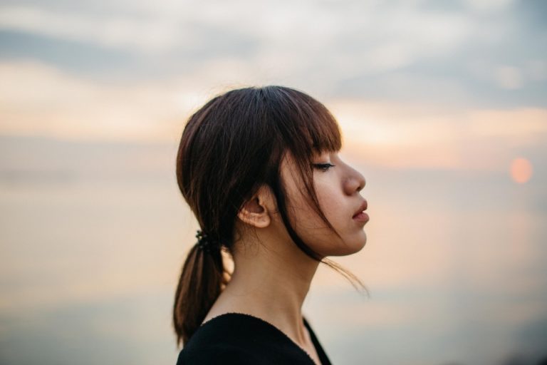 woman with bangs looking to the side by sunset