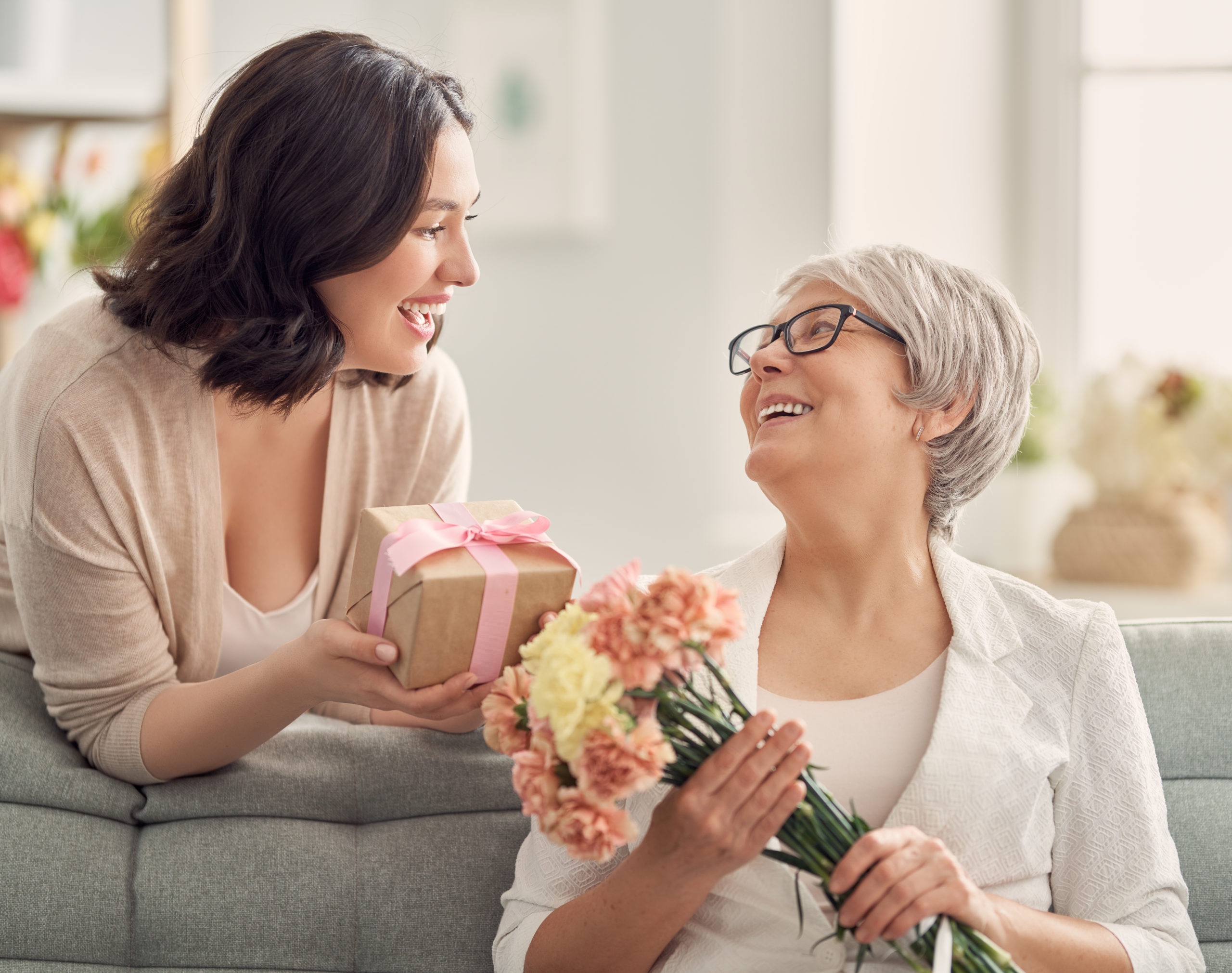 woman giving flowers and present to her mother