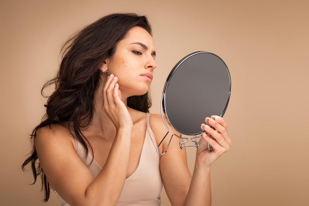 A woman looking in the mirror at sun damage and considering ProFractional® laser in Southlake