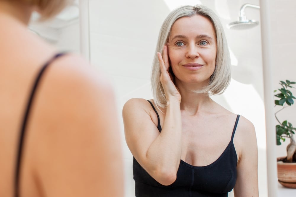 Woman looking in the mirror after facelift swelling has gone down