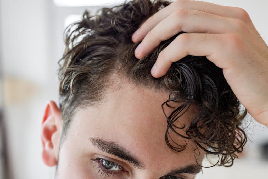 Man checking his hair growth after PRP hair treatments.